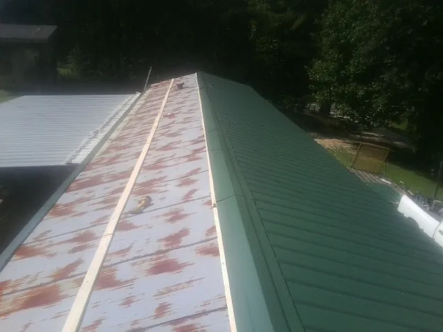 Old rusted panels beside newly installed green metal roofing — Wind Damage Roof Repair by Roofing Brothers in Galion