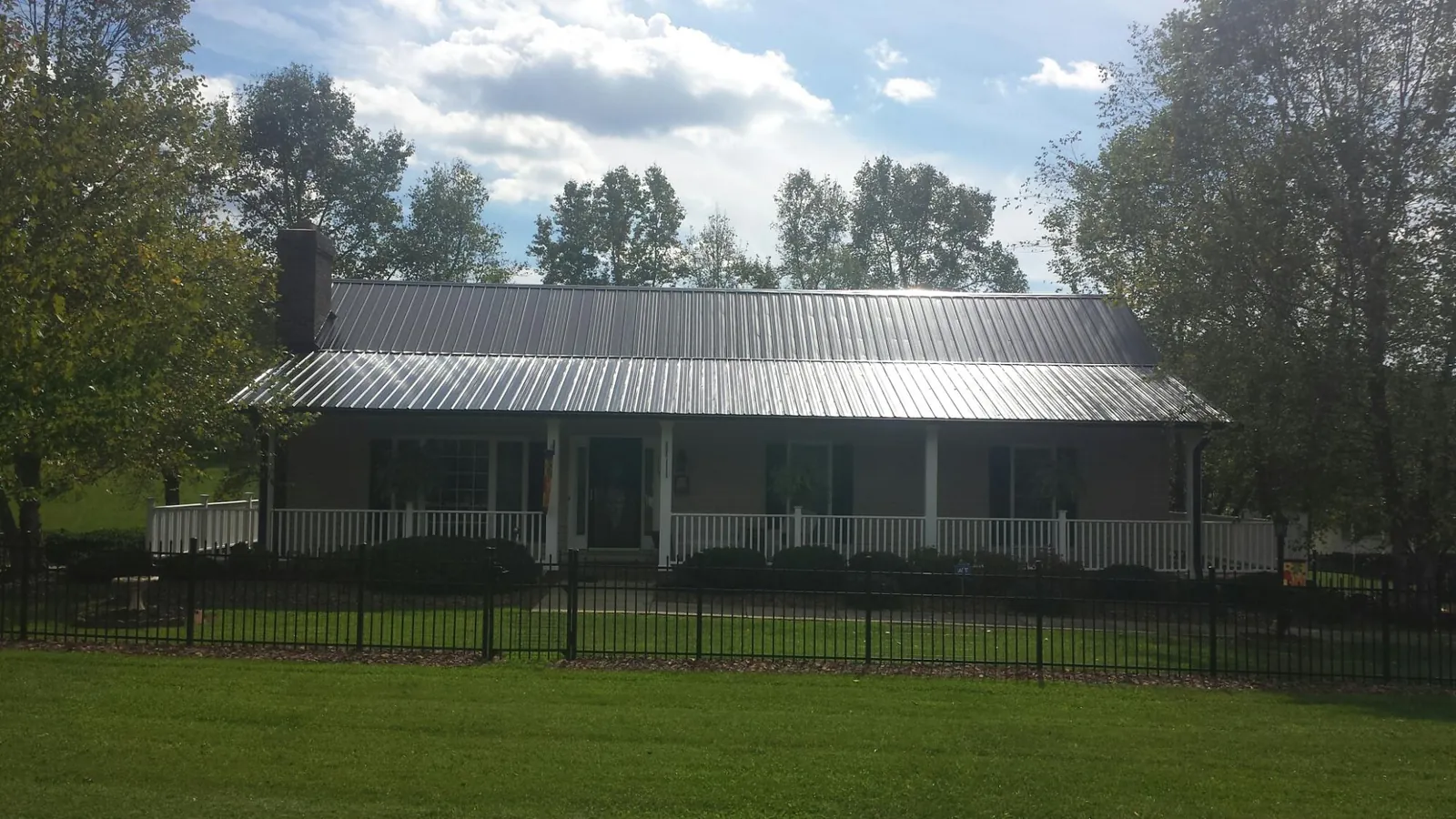 Gray metal roof on a brick ranch with a full width front porch — Gutter Guard Installation work by our crew in Galion
