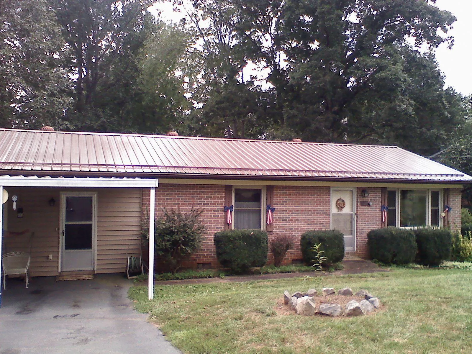 Bronze metal roof and carport on a brick ranch home — Roof Repair work by our crew in Galion