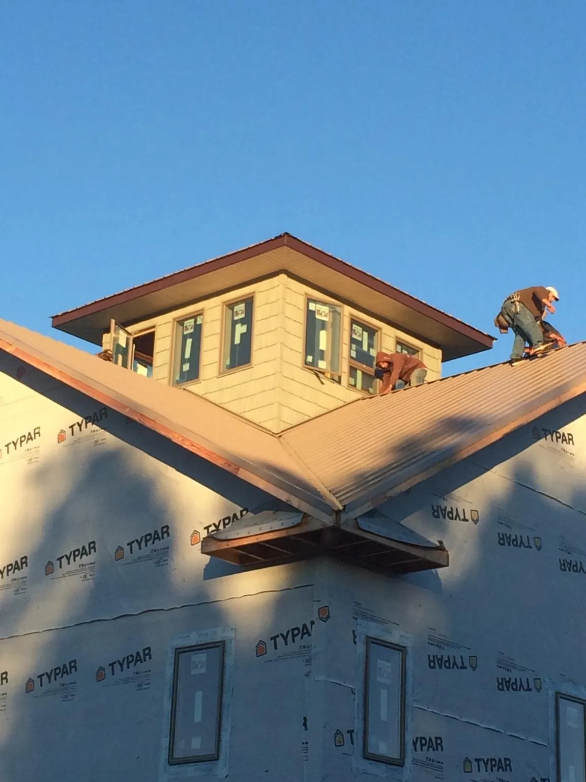 Roofers working around a rooftop cupola on a new metal roof at sunset — Roof Waterproofing in Galion by Roofing Brothers
